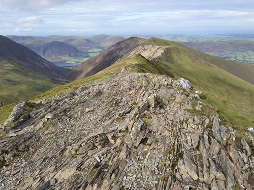 Rocky mountain ridge of Whiteside with green hills and valleys in the background under a partly cloudy sky